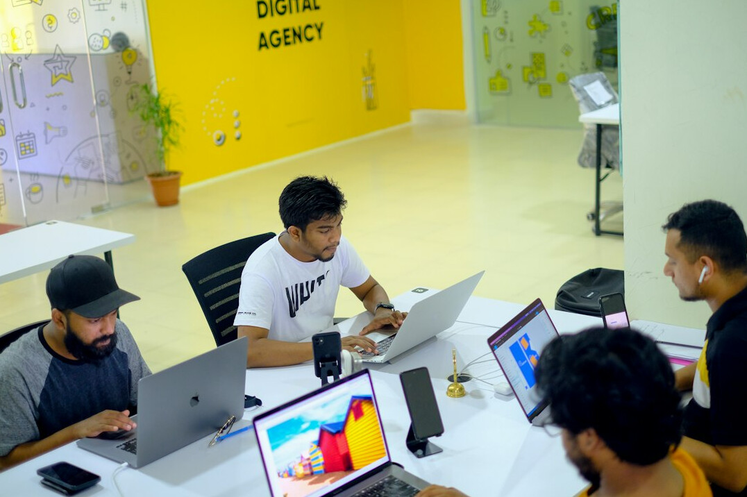 Group of colleagues collaborating around laptops